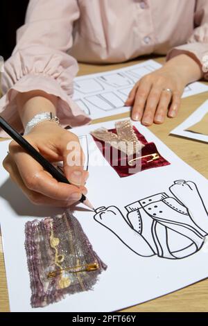 Femme designer de mode dessine des croquis de vêtements sur papier. Banque D'Images