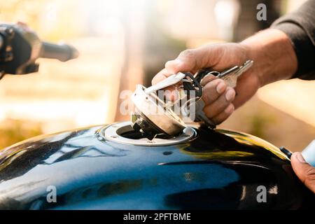 Mains ouvrant le réservoir de gaz de la moto avec la clé. Ouverture manuelle du réservoir de gaz de la moto, motocycliste ouvrant le réservoir de gaz du Banque D'Images