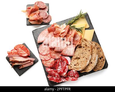Assiettes en ardoise avec assortiment de viandes de charcuterie savoureuses et pain isolés sur fond blanc Banque D'Images