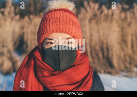 Masque portant le portrait d'une femme asiatique en hiver. Fille en accessoires temps froid, chapeau, écharpe pour morsure de gel Banque D'Images