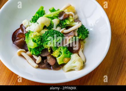 Menu d'aliments sains, champignons sautés, chou-fleur et brocoli, thaï sain mélanger les aliments végétaux sur une assiette blanche. Gros plan, vue du dessus. Banque D'Images