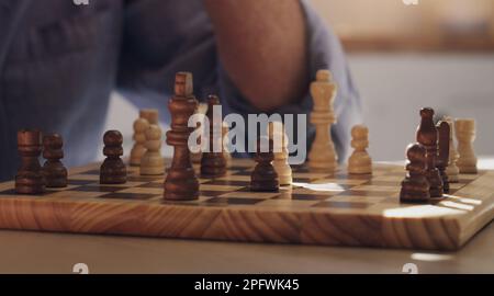 Garder notre cerveau actif avec une partie d'échecs. un homme méconnaissable assis seul et jouant aux échecs dans la cuisine à la maison. Banque D'Images