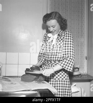Chaussures dans le 1940s. Une jeune femme polit une chaussure avec une brosse à chaussures. La chaussure en cuir qui est portée aura sa saleté enlevée et briller de la cirage de chaussure Suède 1946 Kristoffersson réf Z20-5 Banque D'Images