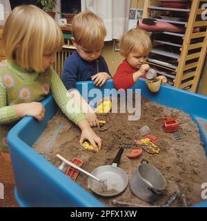 1960s soins de jour. Trois enfants jouent avec des jouets dans une boîte de sable à une école maternelle en Suède 1969. Banque D'Images