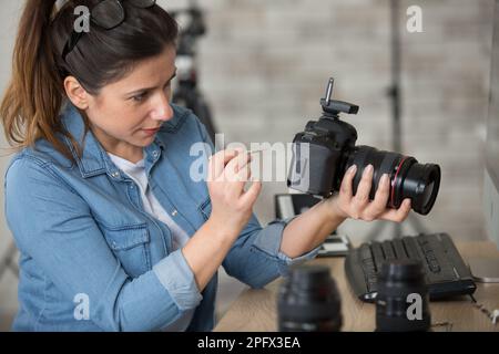 femme photographe nettoyant reflex numérique objectif fisheye Banque D'Images