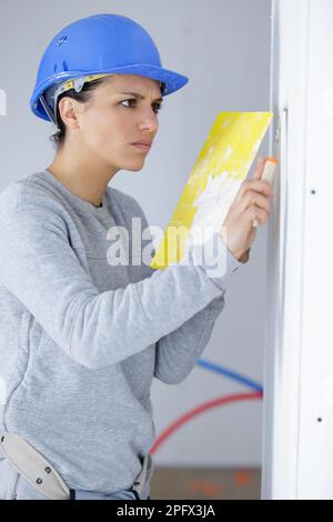 femme travaillant plâtrant les murs de peinture à l'intérieur de la maison Banque D'Images