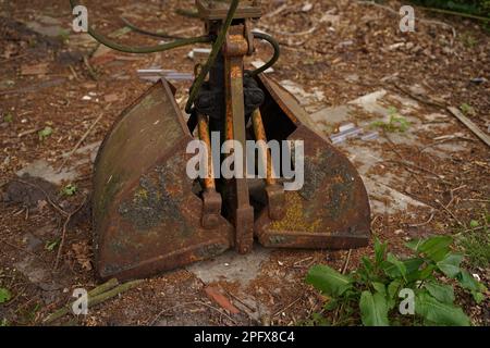 Un ancien godet double abandonné d'une pelle hydraulique dans le jardin. Décoration originale dans le jardin. Banque D'Images