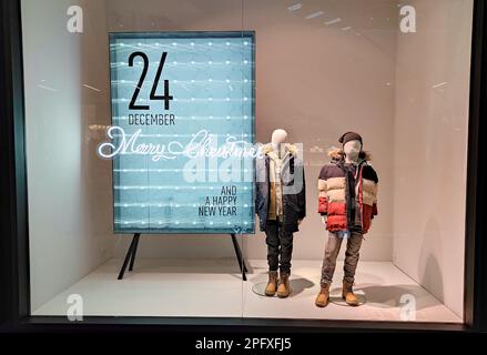 Pologne, Bydgoszcz - 23 décembre 2021 : mannequins pour enfants près du stand de Noël dans la fenêtre du magasin. Collection de vêtements d'hiver Banque D'Images