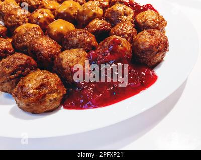 Boulettes de viande fraîches et savoureuses avec sauce aux canneberges sur une assiette blanche. Banque D'Images