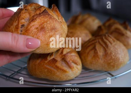 beau dessin sur le pain de pain fraîchement cuit dans les mains d'une femme en gros plan fille tenant le pain examinant ses coupures tout en cuisinant ornement sur une table blanche Banque D'Images