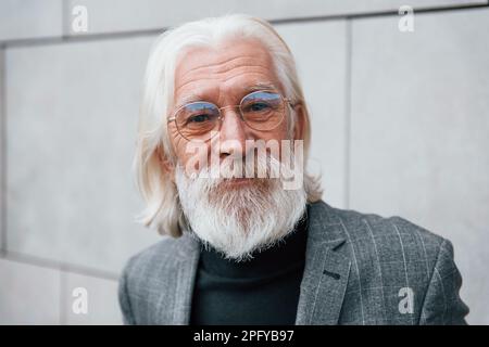 Portrait de l'homme d'affaires senior en vêtements formels, avec des cheveux gris et une barbe debout à l'extérieur Banque D'Images