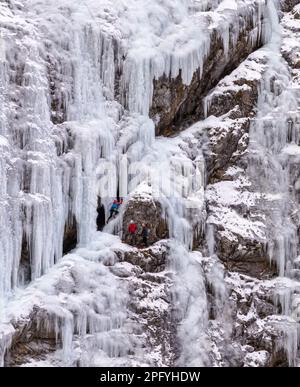 Sappada, Italie - 30 décembre 2022: Trois grimpeurs grimpent le visage glacé d'une montagne en hiver Banque D'Images