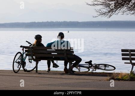 Seattle, Washington, États-Unis. 19th mars 2023. Un couple apprécie le temps de printemps tout en prenant un repos pendant une promenade en vélo le long de la piste Alki. Crédit : Paul Christian Gordon/Alay Live News Banque D'Images