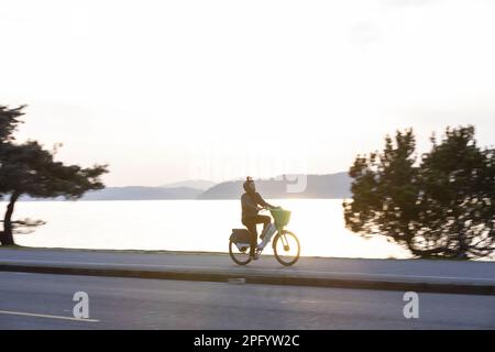 Seattle, Washington, États-Unis. 19th mars 2023. Une jeune femme fait un vélo électrique le long de la piste Alki par temps chaud au printemps. Crédit : Paul Christian Gordon/Alay Live News Banque D'Images