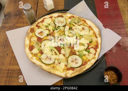 Une merveilleuse pizza à croûte mince moyenne avec différents types de légumes frais et de pomodoro sur une table en bois colorée Banque D'Images