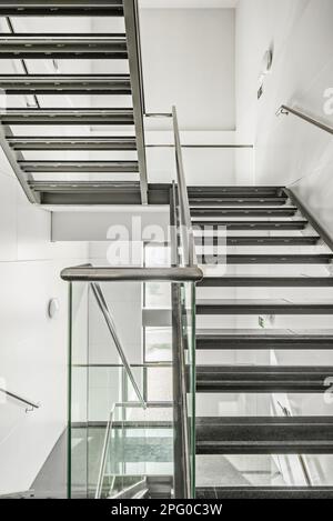 Escaliers légers en acier inoxydable, verre trempé, rails en acier, fenêtres, paliers et marches en granit noir poli dans un bureau b Banque D'Images