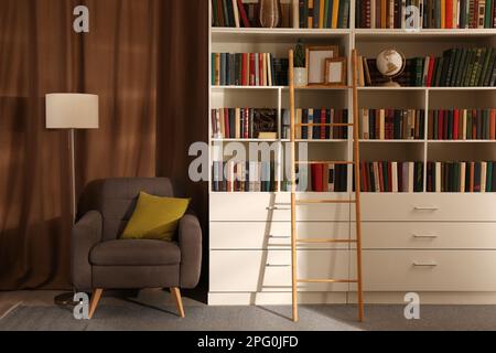 Intérieur confortable de bibliothèque avec collection de différents livres sur des étagères et un endroit confortable pour lire Banque D'Images