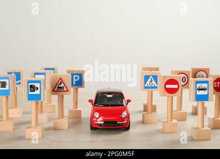 Beaucoup de panneaux de route miniatures différents et voiture sur table en bois, espace pour le texte. École de conduite Banque D'Images