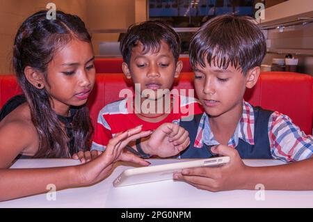 3 enfants adorables, des tweens, 2 enfants Khmers et 1 garçons de race mixte (cambodgien - américain) choisissent leur nourriture. Phnom Penh, Cambodge. Crédit : Kraig Lieb Banque D'Images