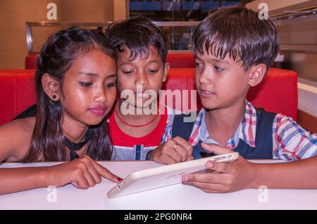 3 enfants adorables, des tweens, 2 enfants Khmers et 1 garçons de race mixte (cambodgien - américain) choisissent leur nourriture. Phnom Penh, Cambodge. Crédit : Kraig Lieb Banque D'Images