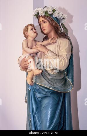 Statue de Marie et le bébé Jésus célébrant Marie au mois de mai avec une couronne de fleurs sur sa tête à Saint Église catholique de Joseph. Banque D'Images