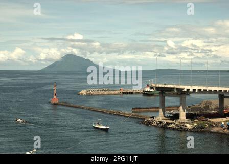 Vue sur la baie de Manado avec le mont Manado Tua au premier plan d'un phare et d'une partie du pont Soekarno en construction dans la zone côtière de Manado, au nord de Sulawesi, en Indonésie. Banque D'Images