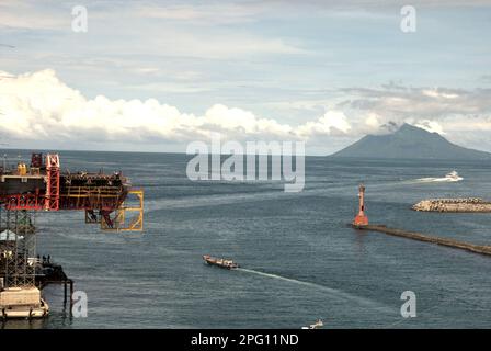 Vue sur la baie de Manado avec le mont Manado Tua au premier plan d'un phare et d'une partie du pont Soekarno en construction dans la zone côtière de Manado, au nord de Sulawesi, en Indonésie. Banque D'Images