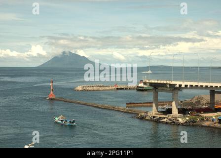 Vue sur la baie de Manado avec le mont Manado Tua au premier plan d'un phare et d'une partie du pont Soekarno en construction dans la zone côtière de Manado, au nord de Sulawesi, en Indonésie. Banque D'Images