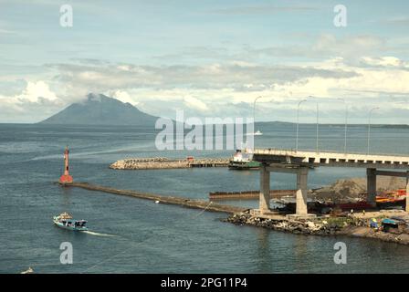 Vue sur la baie de Manado avec le mont Manado Tua au premier plan d'un phare et d'une partie du pont Soekarno en construction dans la zone côtière de Manado, au nord de Sulawesi, en Indonésie. Banque D'Images