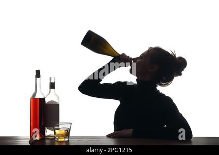 Dépendance à l'alcool. Femme buvant du vin mousseux à la bouteille sur fond blanc Banque D'Images