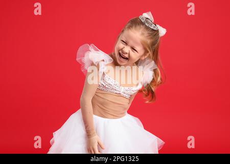 Jolie fille en robe fée avec diadem sur fond rouge. Petite princesse Banque D'Images