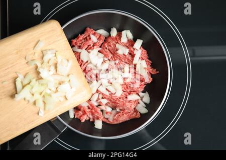 Ajout d'oignon haché sur une poêle avec de la viande hachée crue, vue de dessus Banque D'Images