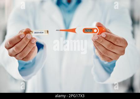 Combattre l'infection avec ceci. Un scientifique tenant une ampoule avec 2019-nCov dessus et un thermomètre. Banque D'Images