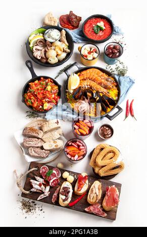 Concept typique de tapas espagnoles. Le concept inclut jamon, chorizo saucisse, brushettas, bol avec olives, crevettes, faire une casserole avec de la paella, du fromage, de la sangria et des churros Banque D'Images