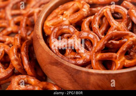 Craquelins bretzels croustillants avec cristaux de sel dans un bol en bois. En-cas traditionnel à la bière en gros plan Banque D'Images