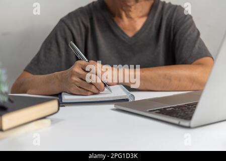 Femme mains avec stylo écrire sur le carnet dans le bureau.apprentissage, éducation et travail.écrit des objectifs, des plans, faire à faire et liste de souhaits sur le bureau. Banque D'Images