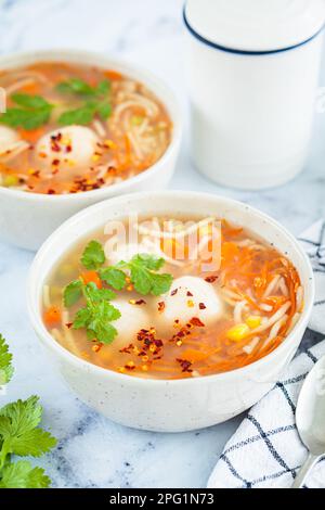 Soupe de boulettes de pommes de terre avec nouilles et légumes dans un bol blanc, fond blanc. Concept alimentaire végétalien. Banque D'Images