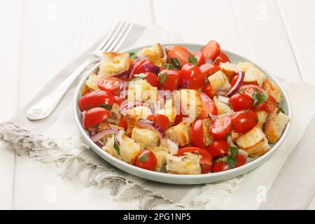 Salade végétarienne de tomates cerises, pain rassis, oignon, huile d'olive et jus de tomate dans une assiette sur la table. Horizontale Banque D'Images