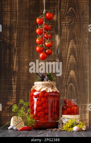 Tomates cerises marinées en pots et épices sur fond de bois Banque D'Images