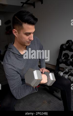 Jeune homme faisant Bicep boucles à la maison garage gym Banque D'Images