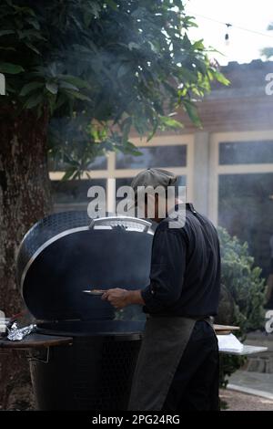 Homme asiatique en uniforme cuisiniers sur le grill à l'extérieur. Personnel de cuisine, Banque D'Images