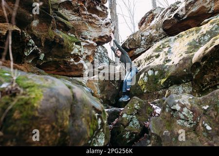 Enfants grimpant sur des rochers lors d'une randonnée en forêt Banque D'Images