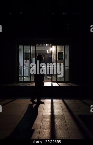 Une silhouette détourée qui marche dans un environnement urbain sombre. Banque D'Images