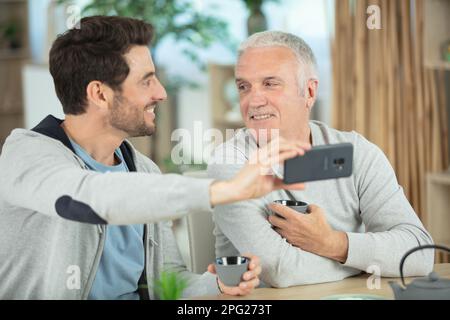 heureux fils barbu prenant le selfie avec un père gai à la retraite Banque D'Images