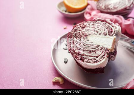 Demi-radicchio sur plaque sur fond de table rose, bordure Banque D'Images