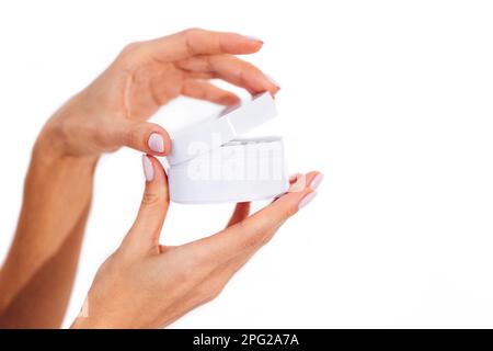 Gros plan extrême de belles mains féminines gracieuses avec manucure blanche tenant le modèle de boîte ronde pour produit de beauté. Arrière-plan blanc. Isolé. F Banque D'Images