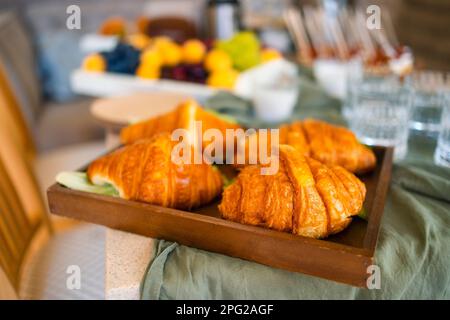 Table suisse à la fête. Gros plan des croissants avec des légumes verts et des verres avec des boissons. Bougies, chaises et assiettes, cupcakes, en-cas, fruits, raisins Banque D'Images