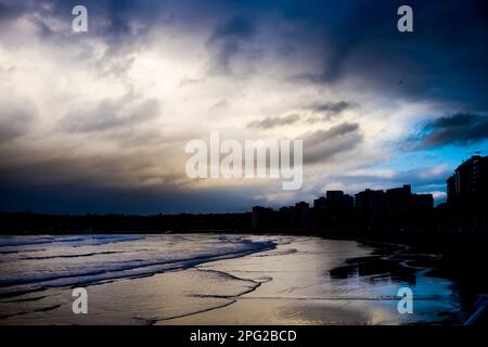 Une vue de la silhouette générale de la ville de Gijon et de la plage avec un ciel spectaculaire en soirée. Banque D'Images