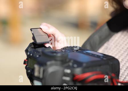 Gros plan d'une main de photographe en insérant une carte compacte dans l'appareil photo Banque D'Images