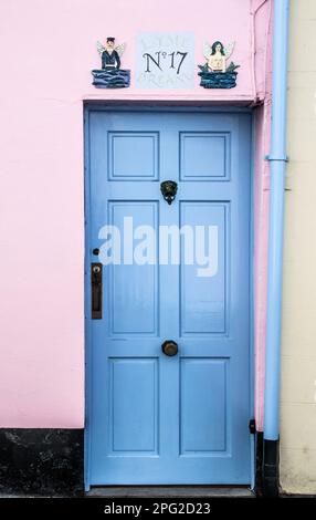 Une porte bleue et rose dans la ville balnéaire et port de pêche de Lyme Regis, Dorset. Au-dessus de la porte se trouvent un capitaine de mer et une sirène avec des ailes d'ange. Banque D'Images